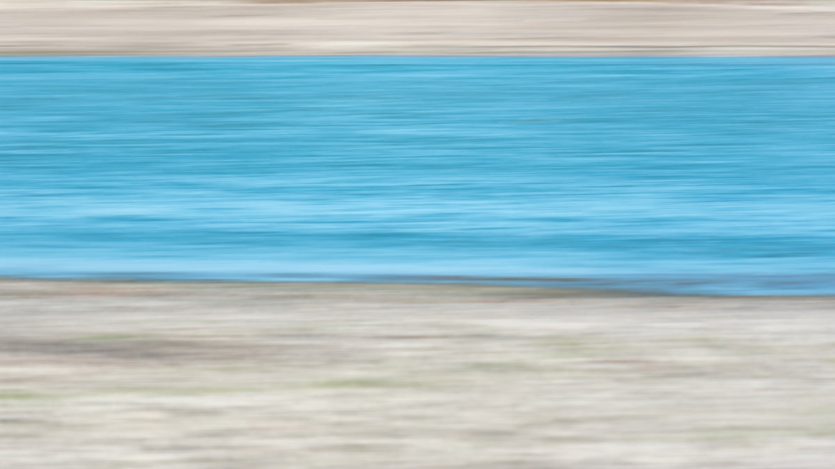 An abstract, horizontally blurred scene with a large bright blue band across the center and warm beige/tan areas above and below it.